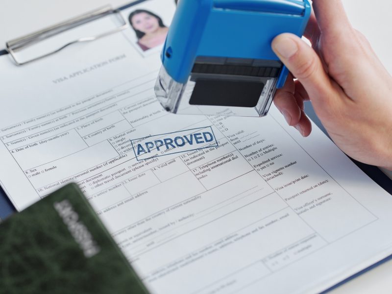 Close-up shot of unrecognizable person working as consular officer in embassy approving visa application putting seal on it